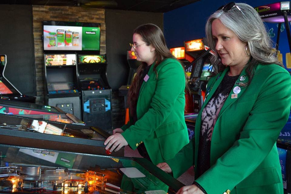Chamber ambassadors playing pinball at a ribbon cutting event for a Paragould business.